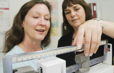 A care provider weighs a patient on a scale
